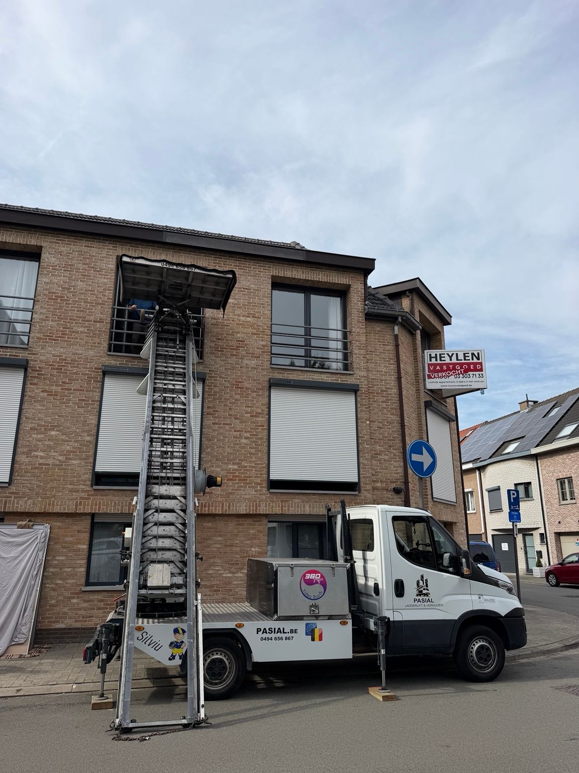 Pasial ladderlift opgesteld bij een woning, met de liftwagen naast de gevel