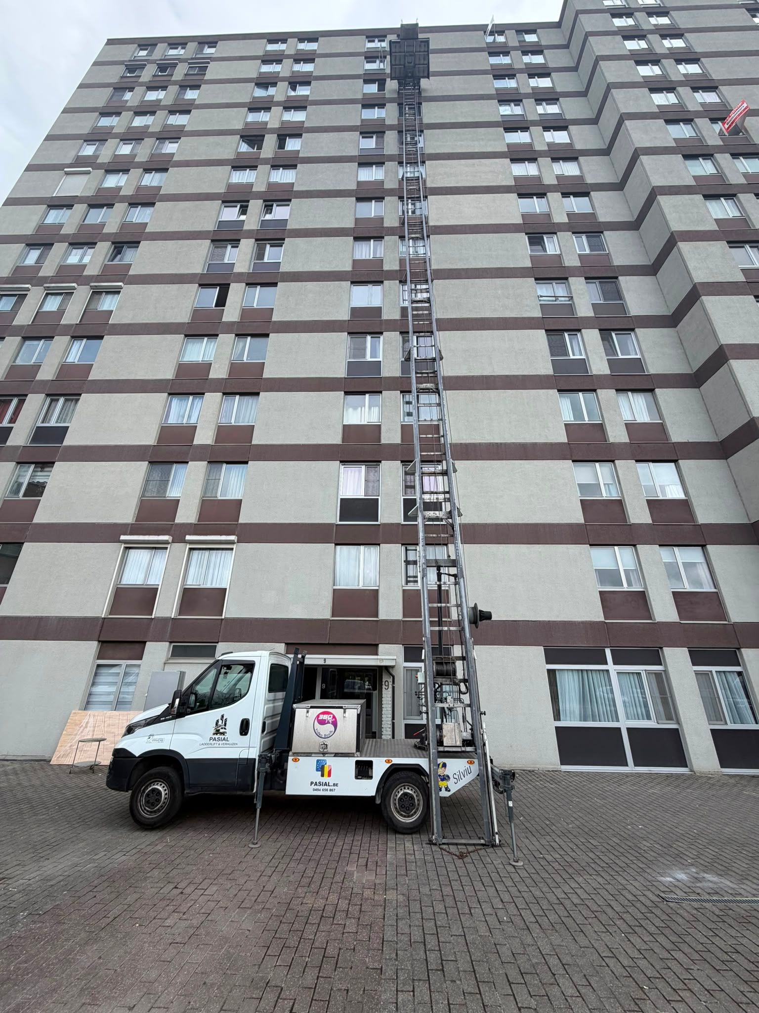 Pasial ladderlift hoog uitgeschoven langs een appartementsgebouw